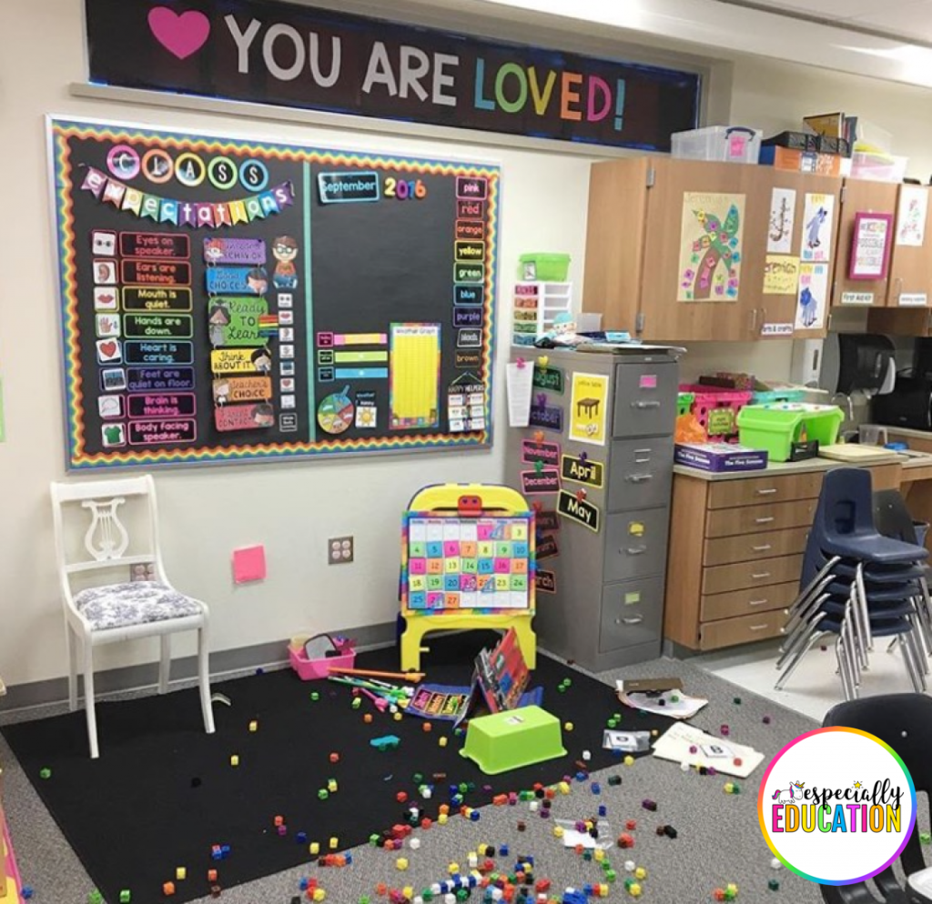 A messy classroom with boxes of supplies on the floor