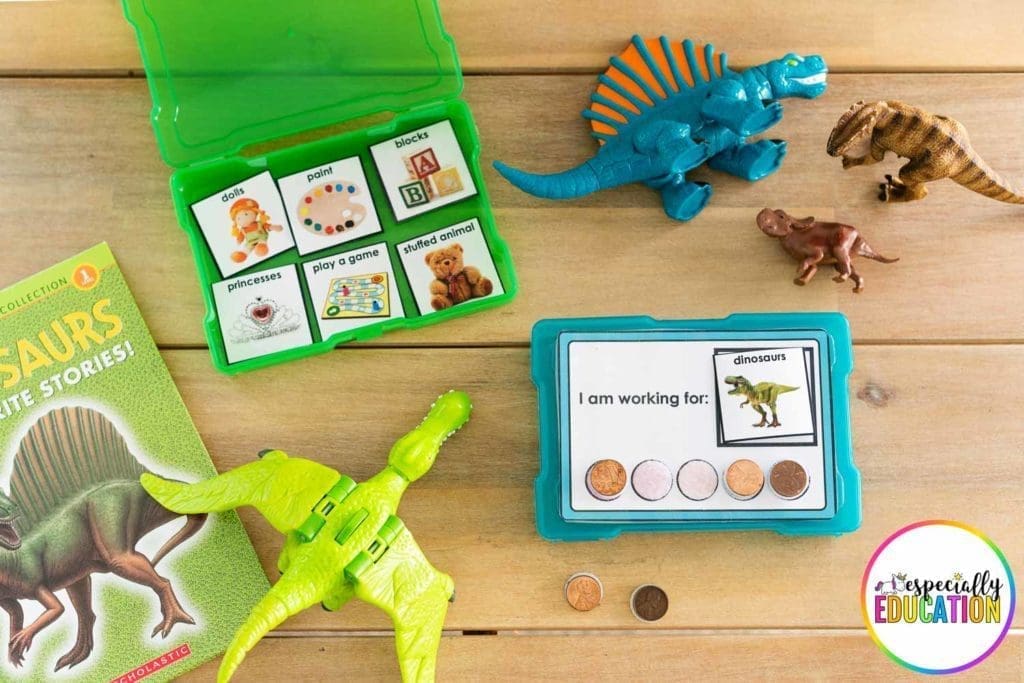 Dinosaur toy and book next to colorful small boxes filled with tokens