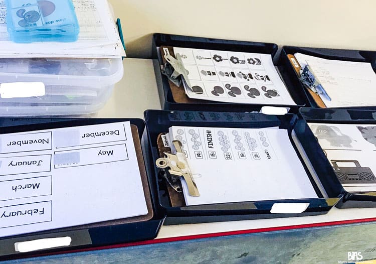 Five plastic "in-trays" each containing a special education data collection pack for a different student.