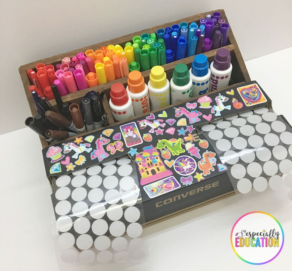 A pencil holder with pens and inks and a cardboard box decorated with fun stickers