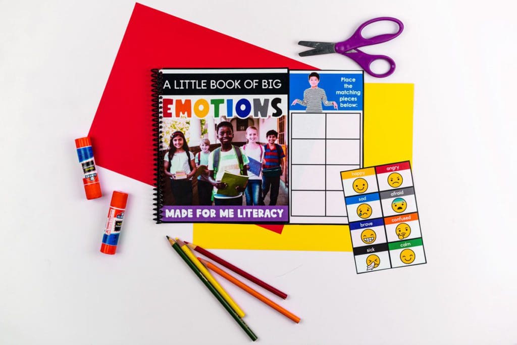 Elementary students on the cover of a notebook on top of a desk surrounded by school supplies