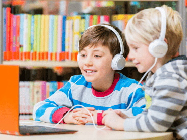 Two children in a library listening to an audio book together.