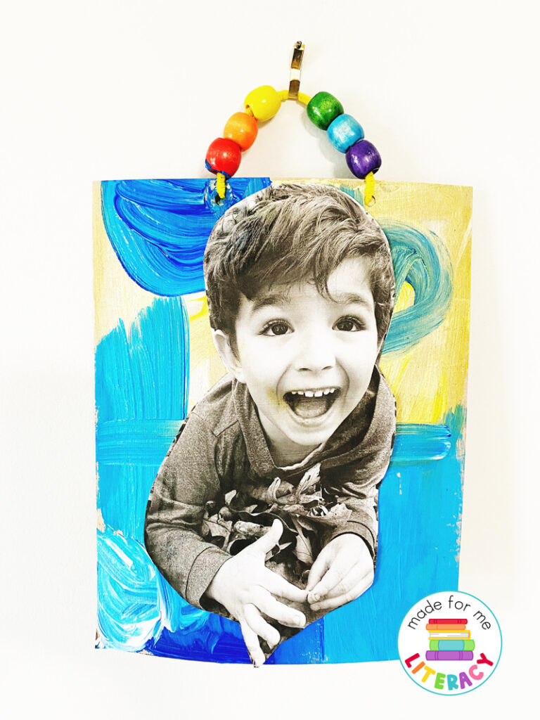 A handmade portrait of a laughing little boy hung on the wall with a rainbow beaded hanger.