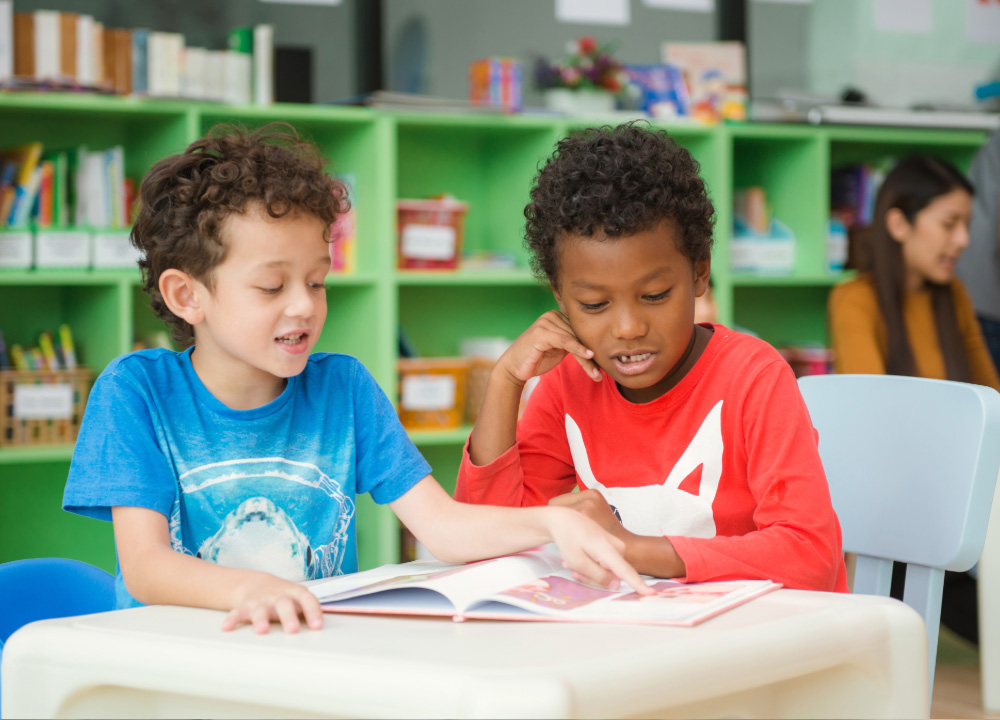 Two young boys enjoying a book in a classroom.