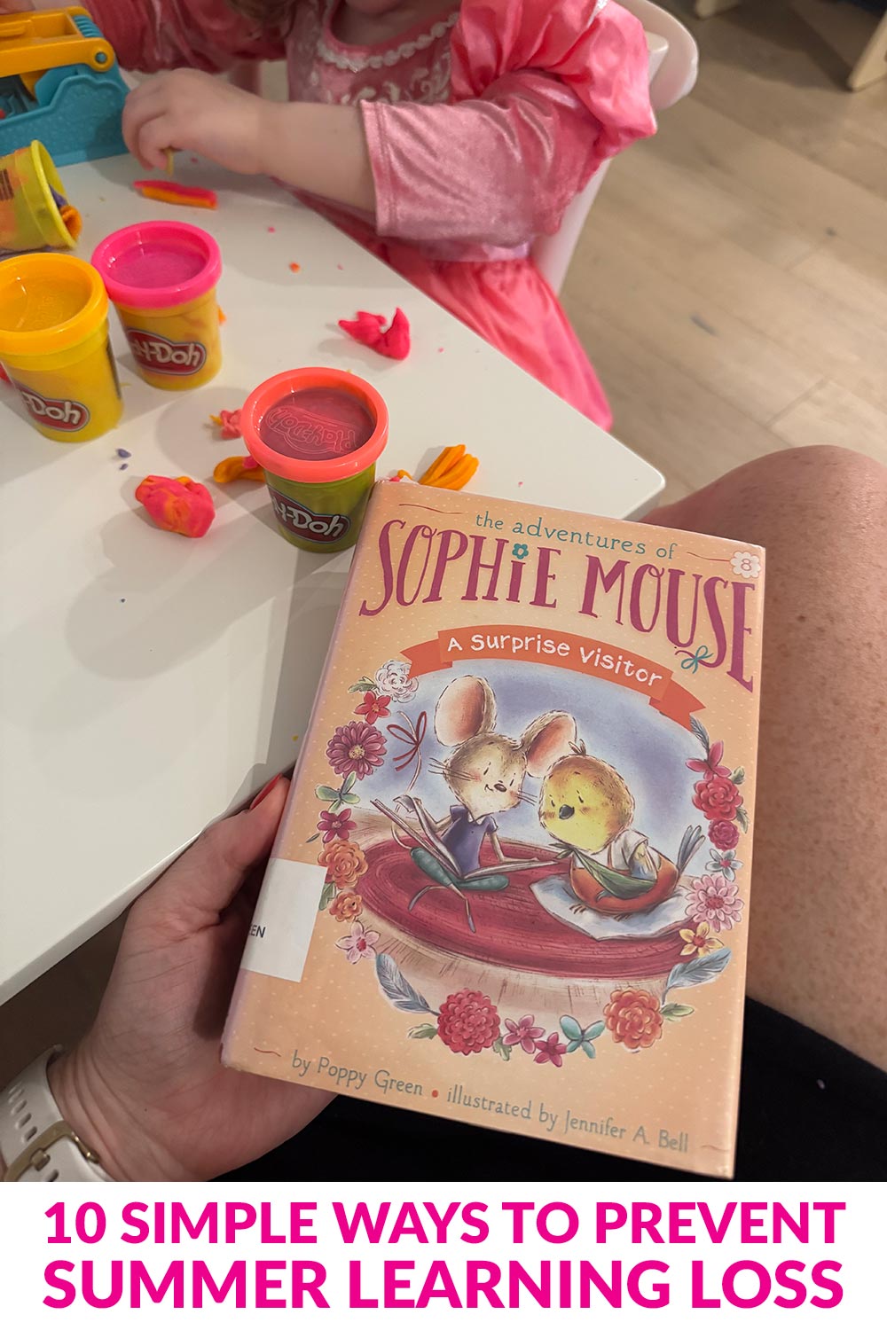 Mother reading a chapter book while her child sits at a table playing with play-doh