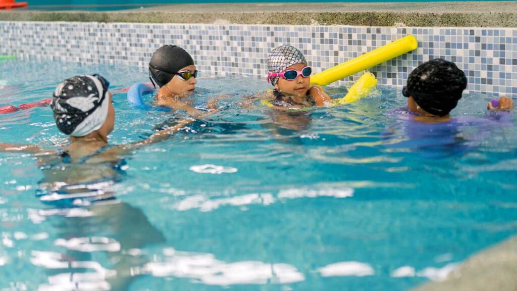 Children participating in a summer swimming activity, building social and motor skills in a structured group setting