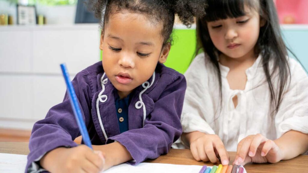 Students working together on a writing and coloring activity at a classroom table