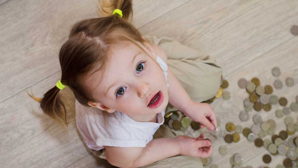 Young child explores a collection of coins during hands-on money learning.